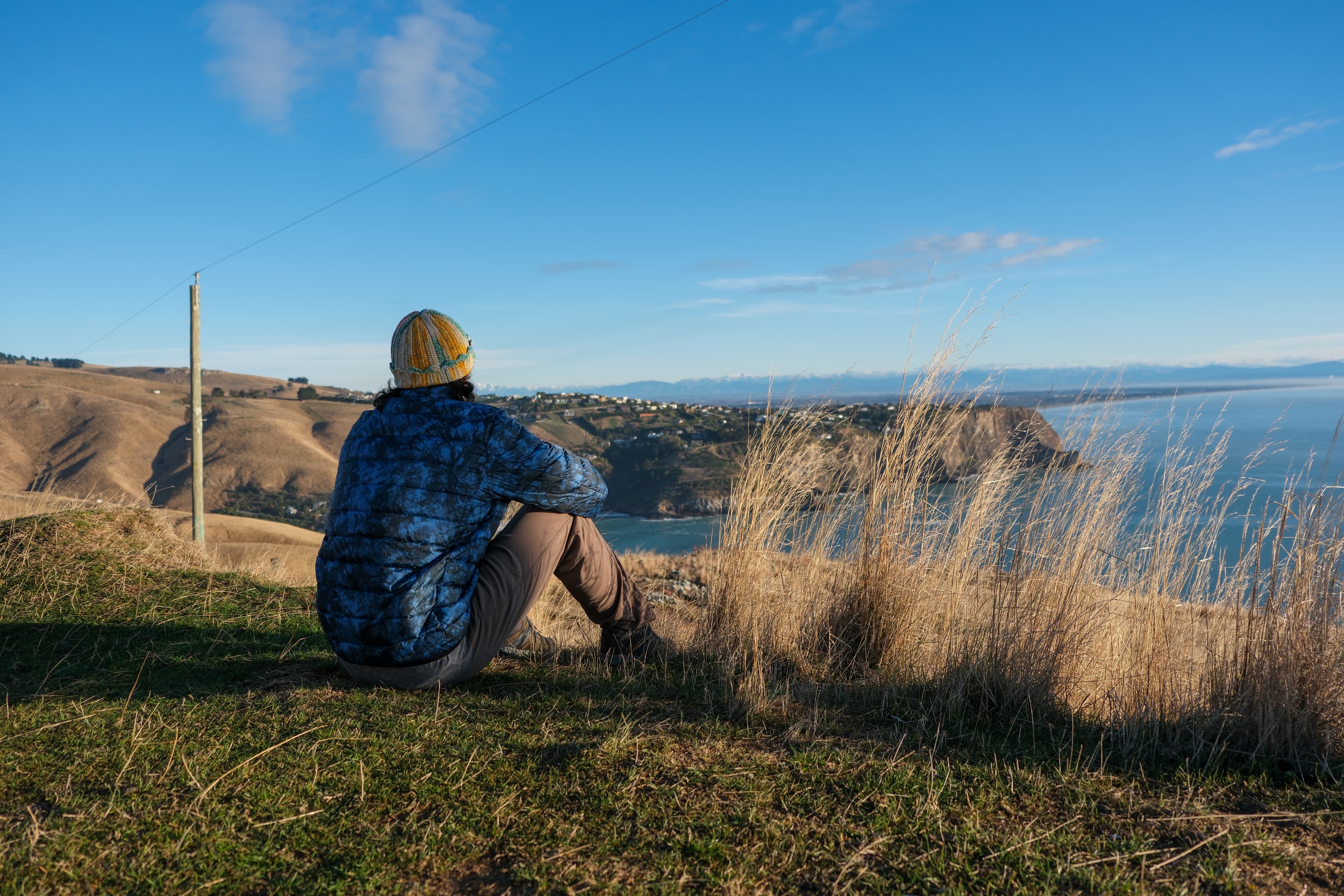 18mm · f/3.2 · 1/1250s · ISO 160
FUJIFILM X-T5 · XF18-55mmF2.8-4 R LM OIS · May 24, 2024
Person overlooks coastal Christchurch cliffs and distant snowy mountains.
Christchurch, New Zealand
© Brandon Cook