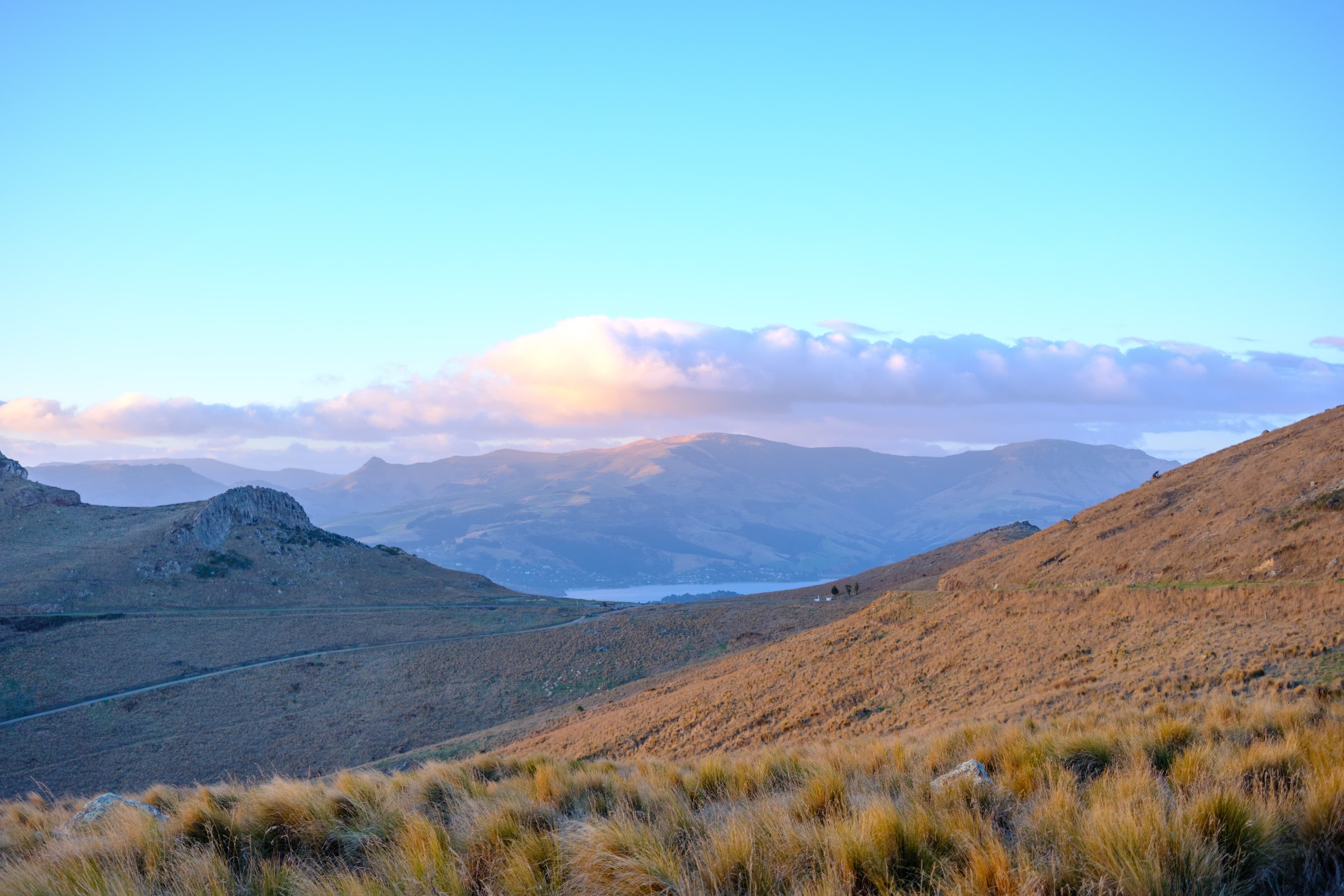 27mm · f/2.8 · 1/320s · ISO 200
FUJIFILM X-T5 · XF27mmF2.8 R WR · May 25, 2024
Golden hills overlooking distant mountains under a soft sunset sky.
Christchurch, New Zealand
© Brandon Cook