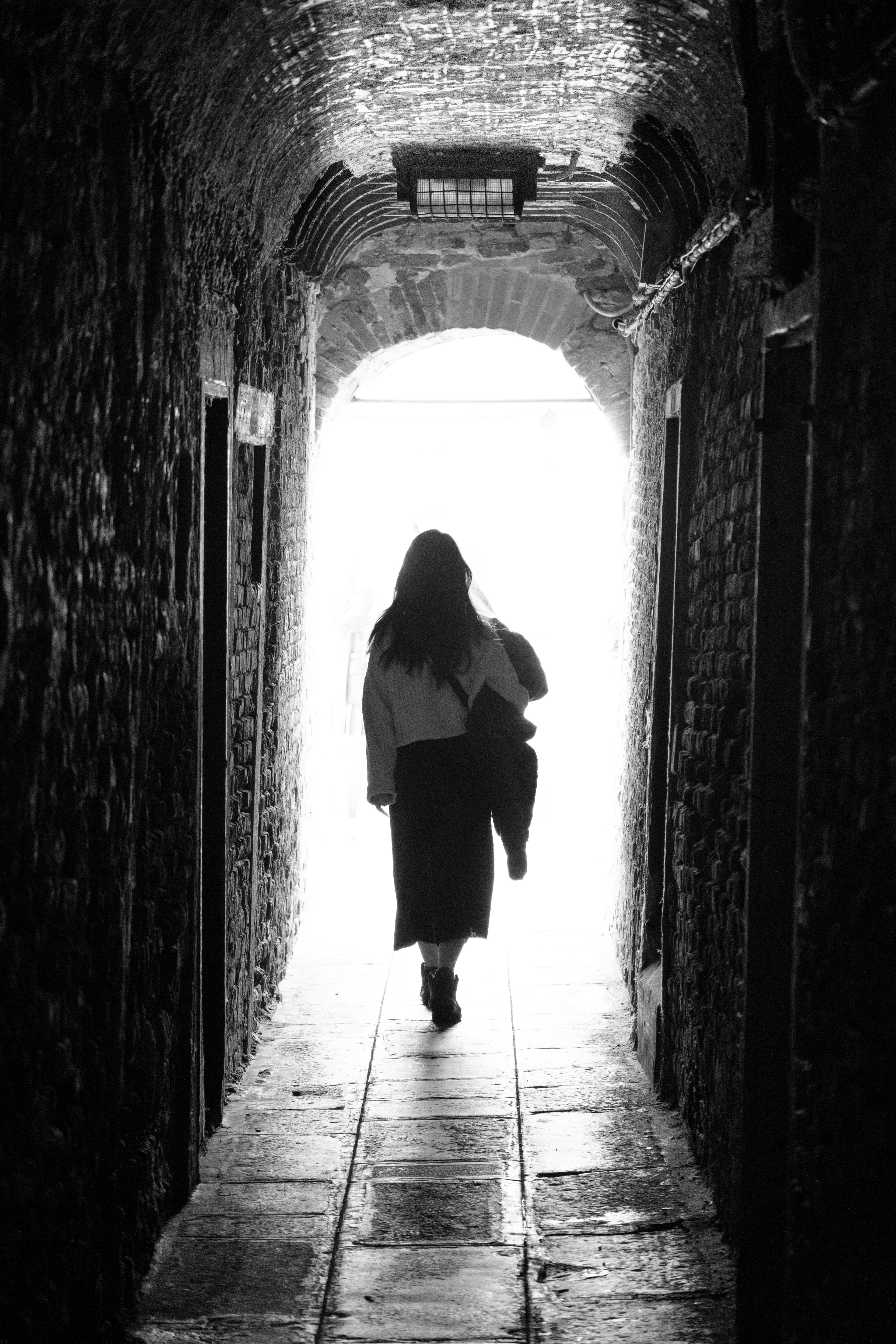 70mm · f/4 · 1/125s · ISO 4000
FUJIFILM X-T5 · XF70-300mmF4-5.6 R LM OIS WR · Oct 19, 2024
Woman walking through a dark stone tunnel towards bright light.
Venice, Italy
© Brandon Cook