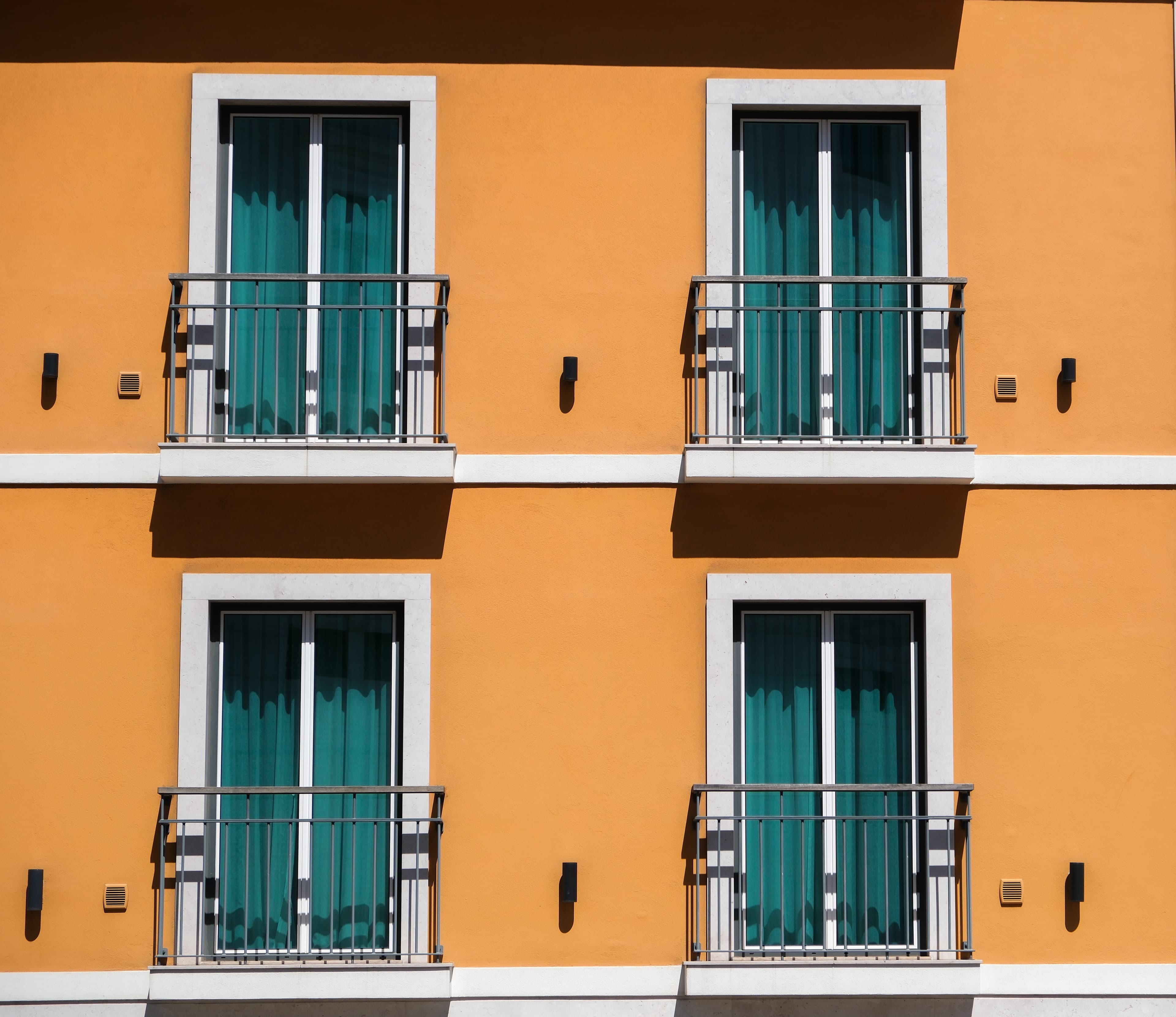 53mm · f/5 · 1/2000s · ISO 200
FUJIFILM X-T5 · XF18-55mmF2.8-4 R LM OIS · May 12, 2024
Four teal-curtained balconies on a vibrant orange Lisbon building.
Lisbon, Portugal
© Brandon Cook
