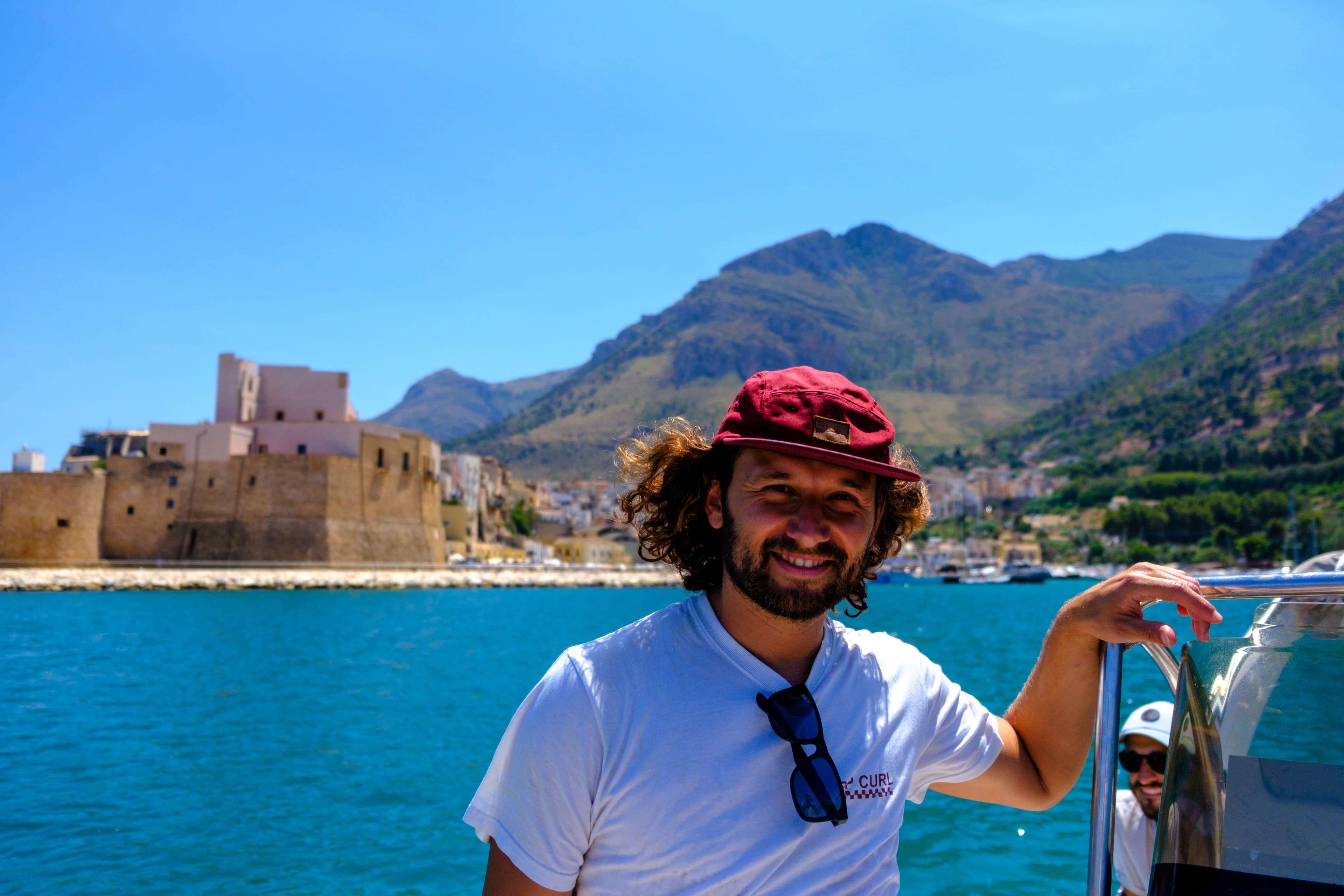 18mm · f/2.8 · 1/8000s · ISO 200
FUJIFILM X-T5 · XF18-55mmF2.8-4 R LM OIS · Jul 19, 2024
Smiling man on boat with scenic coastal castle and mountains.
Sicily, Italy
© Brandon Cook
